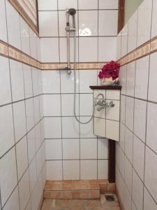 a shower in a tiled bathroom with a vase of flowers at Résidence Tamaumia - Bungalow in Hakamui