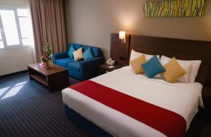 Pokój hotelowy z dużym łóżkiem i niebieskim krzesłem w obiekcie Best Western Premier Muscat w Maskacie