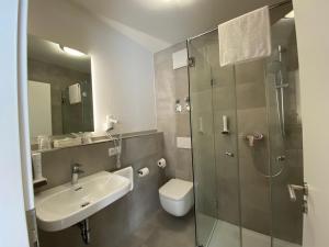 ein Bad mit einem Waschbecken, einem WC und einer Dusche in der Unterkunft Hotel-Pension Scharl am Maibaum in Eitting