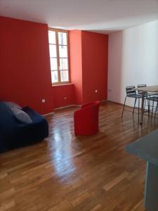 ein Wohnzimmer mit roten Wänden und Holzboden in der Unterkunft Appartement 1er étage in Largentière
