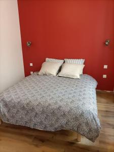 Bett in einem Zimmer mit roter Wand in der Unterkunft Appartement 1er étage in Largentière