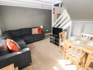 a living room with a black couch and a table at Sun Rise Cottage in Saundersfoot