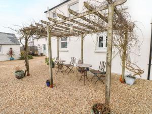 a patio with a table and chairs under a pergola at Sun Rise Cottage in Saundersfoot