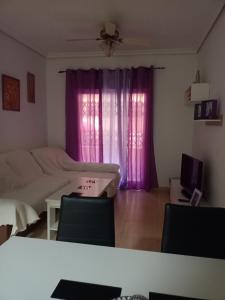 - une chambre avec des rideaux violets, un lit et une télévision dans l'établissement Alojamiento roquetas de mar, à Roquetas de Mar