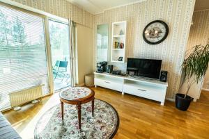 a living room with a tv and a table and a stool at Ramaus Poilsio Apartamentai in Palanga