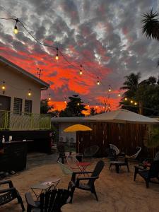 a patio with chairs and an umbrella and a sunset at Le Passiflore in Kumak