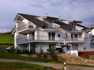 een groot wit huis met balkons op een heuvel bij 5 Sterne Ferienwohnung Bergahorn mit Sauna in Oberstaufen