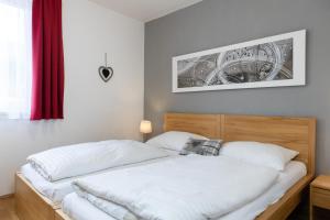 Schlafzimmer mit einem Bett mit weißer Bettwäsche in der Unterkunft Apartment Adler Resort by Alpin Rentals in Kaprun