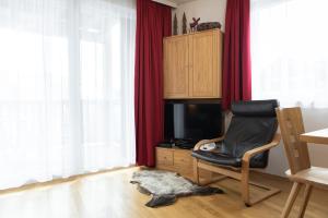 ein Wohnzimmer mit einem Stuhl und einem TV in der Unterkunft Apartment Adler Resort by Alpin Rentals in Kaprun