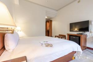 a bedroom with a large white bed and a flat screen tv at Spring Hotel in Jiaoxi