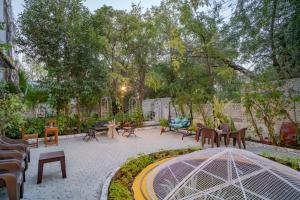 un patio con mesas y sillas en un jardín en Hotel Ambavgarh Palace, en Udaipur
