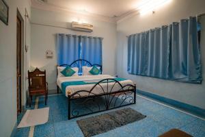 Un dormitorio con una cama y una ventana con cortinas azules. en Hotel Ambavgarh Palace, en Udaipur