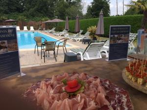 een tafel met een bord eten naast een zwembad bij Hôtel LES LODGES D'EAUZE in Eauze