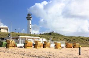 a lighthouse with a bunch of chairs on the beach at Gelijkvloers Vakantieappartement 150m van Strand Egmond aan Zee in Egmond aan Zee