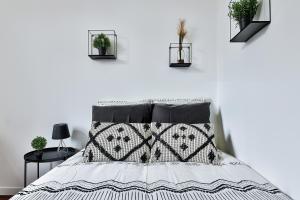 a bedroom with a bed with black and white sheets and plants at Appartement Le Somptueux Bressan - Hyper-Centre in Bourg-en-Bresse