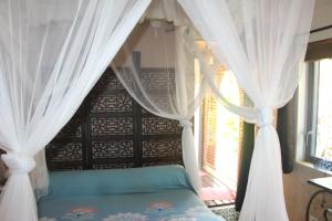 1 dormitorio con cama con dosel y ventana en Lodge Ylang Ylang, LIANE DE JADE 974 -piscine - jacuzzi privatif, en Le Bois de Nèfles