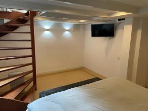 a bedroom with a bed and a staircase with a television at De Boetz in The Hague