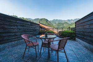 a table and chairs on a patio with mountains in the background at S&N Hotel Sanqingshan in Shangrao