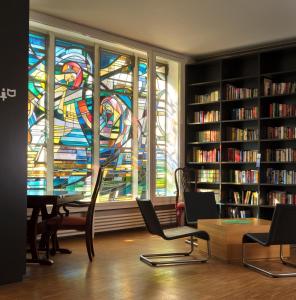 Remerschen的住宿－申根青年旅舍，一个带彩色玻璃窗和桌椅的图书馆