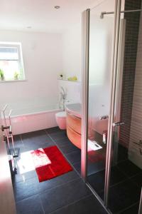 a bathroom with a bath tub and a shower with a toilet at FeWo Glockenstüble mit Schwimmbad und Sauna in Oberstaufen