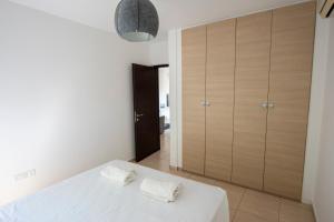 a bedroom with a bed with white sheets and wooden cabinets at Glabur Stays - The Master Atelier - Nicosia City, Free Parking & Wifi, Welcomes You!!! in Nicosia