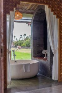 a bath tub in a room with a window at Casa Batu Belig in Seminyak