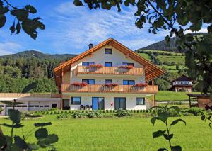 uma grande casa com uma varanda num campo verde em Stiflerhof Apt Alpenrose em Falzes
