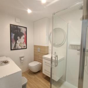 a white bathroom with a shower and a toilet at Apartament Emili VIPOO in Suwałki