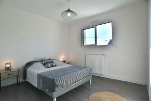 una camera bianca con un letto e una finestra di Les Figuiers - Joli maison pour 8 a Plouër-sur-Rance
