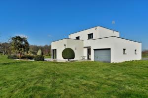 una casa bianca con un ampio cortile verde di Les Figuiers - Joli maison pour 8 a Plouër-sur-Rance