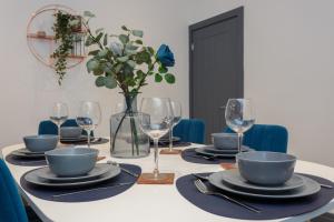 a table with plates and glasses and a vase with flowers at Methuen Mews - 2 double bedroom townhouse within walking distance to beach, on-street parking in Portsmouth in Portsmouth