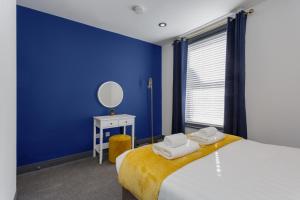 a blue bedroom with a bed and a mirror at Methuen Mews - 2 double bedroom townhouse within walking distance to beach, on-street parking in Portsmouth in Portsmouth