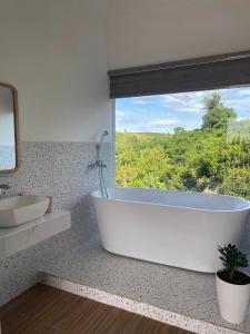 eine weiße Badewanne im Bad mit Fenster in der Unterkunft Dứa Homestay in Bảo Lộc