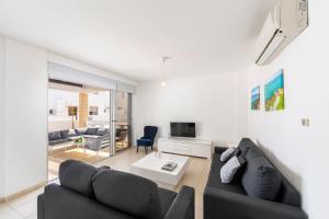 een woonkamer met een zwarte bank en een tv bij Protaras Sapphire Seaside Villa in Protaras