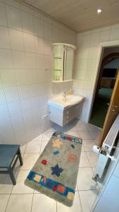 a bathroom with a sink and a mirror and a rug at Ferienwohnung Kaufmann in Oberstaufen