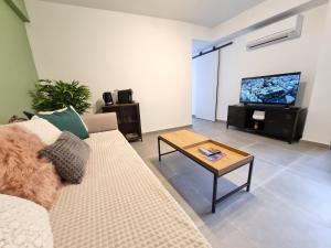 ein Wohnzimmer mit einem Sofa, einem Tisch und einem TV in der Unterkunft Terraza Almería in Almería