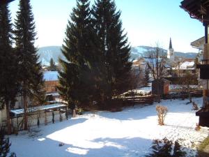 een sneeuwbedekte tuin met bomen en een kerk bij Ferienwohnung Sonnenblick in Oberstaufen