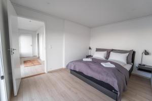 a white bedroom with a large bed and a hallway at Runde Panorama - Ørneredet in Runde