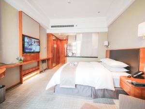 una camera con un grande letto e una televisione di Ramada Plaza Shanghai Pudong Airport - A journey starts at the PVG Airport a Shanghai