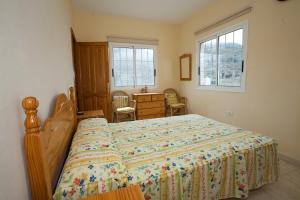 Un dormitorio con una cama y un escritorio y dos ventanas. en Apartamentos Arure Plaza, en Arure