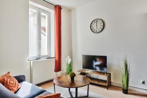 een woonkamer met een bank, een tafel en een klok bij Appartement Le Chaleureux Chalon - Hyper-Centre in Chalon-sur-Saône