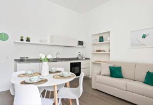 een witte keuken en een woonkamer met een tafel en stoelen bij SOFIA LAKE SUITE in Como