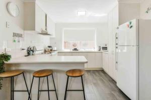 a kitchen with wooden stools and a white refrigerator at Avenue Family Retreat in Rosebud