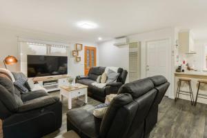 a living room with two couches and a tv at Avenue Family Retreat in Rosebud
