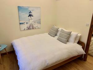 Un dormitorio con una cama blanca con una foto en la pared en Denbrae, en Brackley