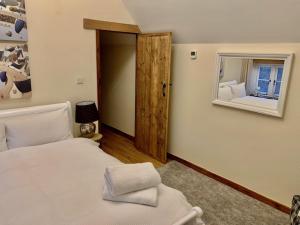 1 dormitorio con cama blanca y espejo en Denbrae, en Brackley