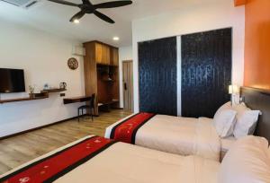 a hotel room with two beds and a tv at Kokol Haven Resort in Kota Kinabalu