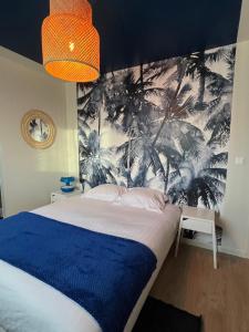 Schlafzimmer mit einem Bett und einem Wandbild von Palmen in der Unterkunft La Belle Mélorienne in Saint-Méloir-des-Ondes