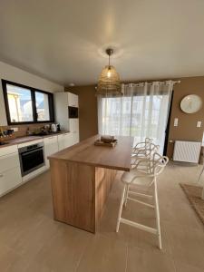 a kitchen with a wooden island with chairs in it at La Belle Mélorienne in Saint-Méloir-des-Ondes