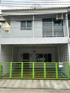 uma casa com uma cerca verde em frente em S Villa @Impact Muangthongthani em Pak Kret